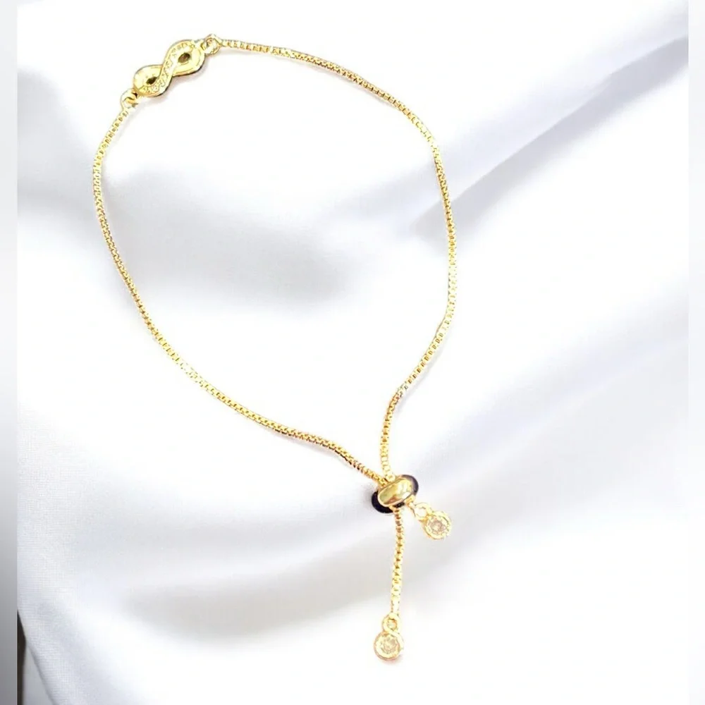Gold tone infinity sliding stopper bracelet with two charms and crystals